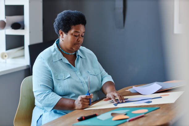 istock Serious mature craftswoman with scissors creating new composition 1564364794
