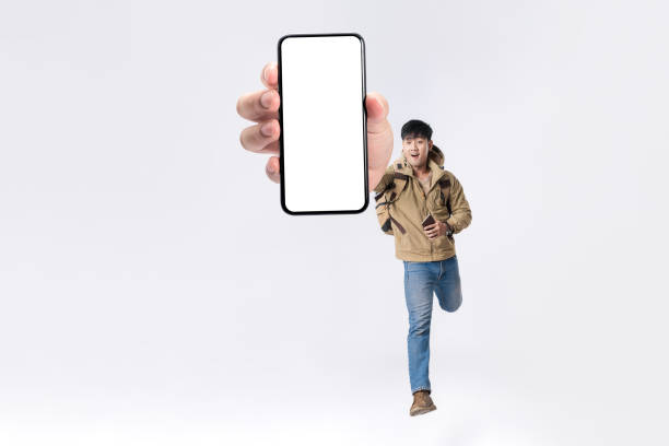 istock Full length excited Asian man backpacker walking with showing cellphone blank screen with empty space for mobile app on screen. Isolated in studio white background. Creative collage. 1564406382