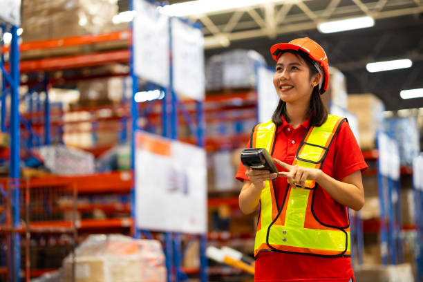 istock Warehouse female staff worker wearing hardhat helmet working on barcode scanner handheld at warehouse factory 1564430827