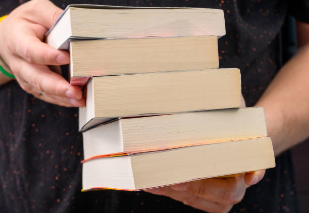 A man holding a stack of books in his hands