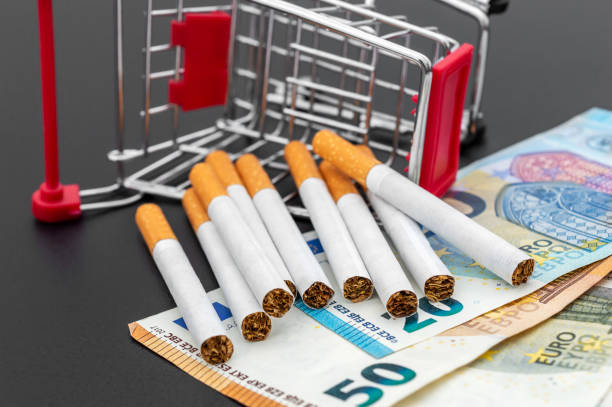Cigarettes with shopping cart and euro on black. stock photo