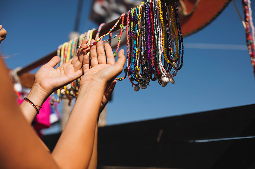 Cropped photo of a woman's hands while she looks at a bunch of necklaces to buy