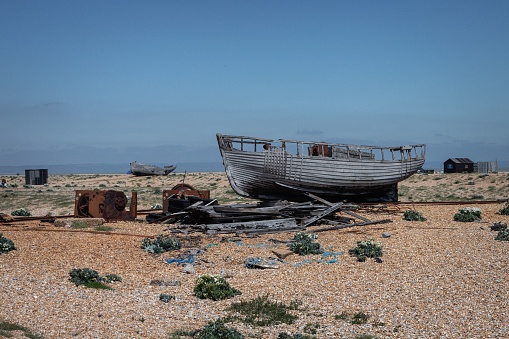 A classic wooden boat stranded on the pebble shore of Dungeness Beach