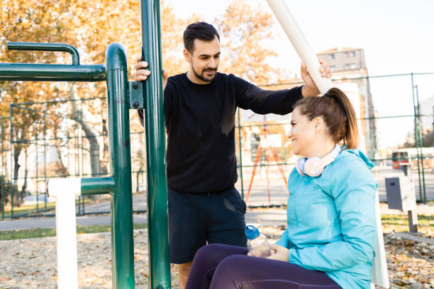 istock Young couple taking a break while exercising at the outdoor gym 1564603369
