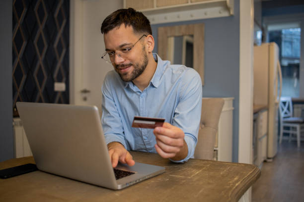 istock Cheerful man doing online shopping 1564604976