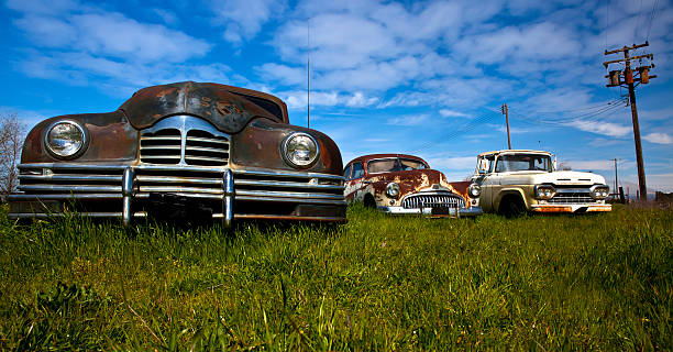 istock Three old classic cars wasting away in a field 156460549