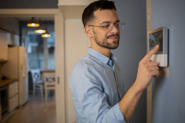 istock Young man adjusts the temperature at home with a device on the wall 1564607091