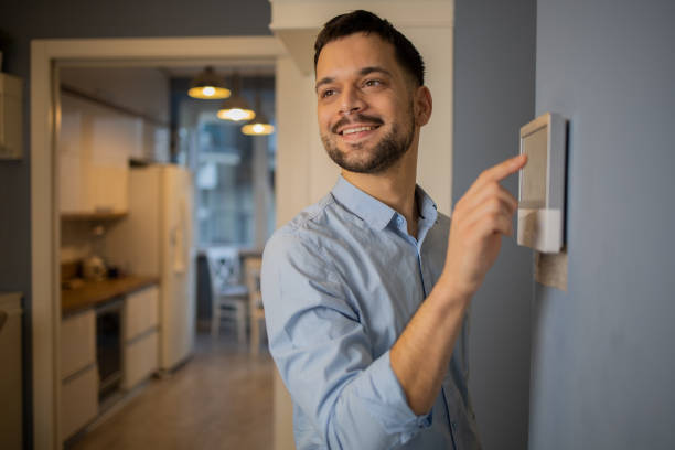 istock Young man adjusts the temperature at home with a device on the wall 1564607156