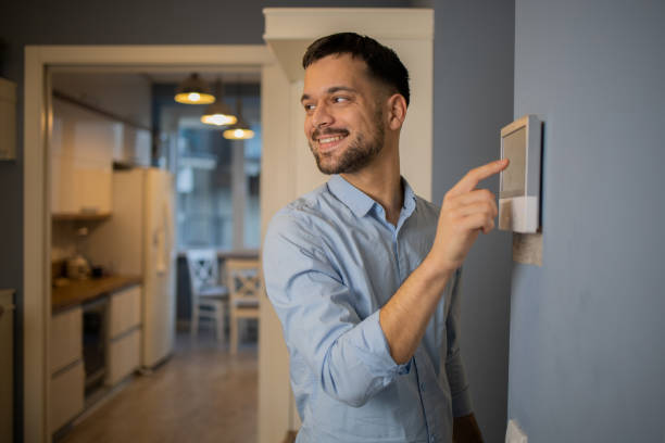 istock Young man adjusts the temperature at home with a device on the wall 1564607168