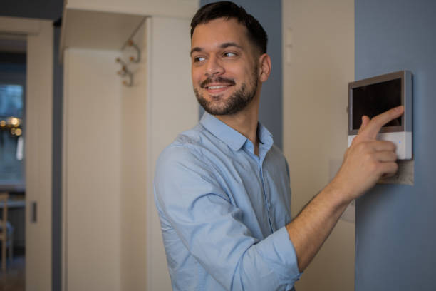 istock Young man adjusts the temperature at home with a device on the wall 1564607169