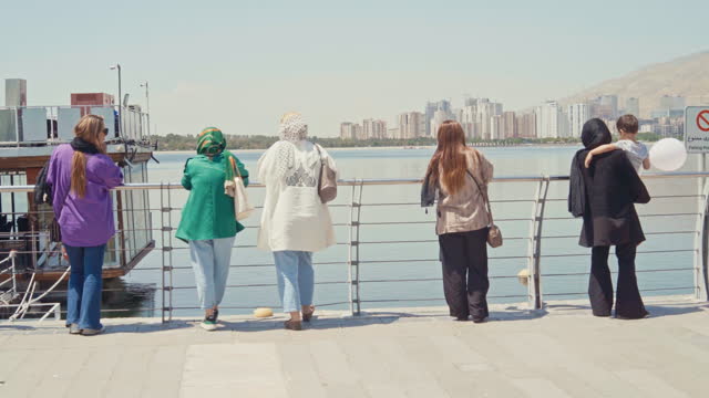Iranian Women standing at the barrier of a lake looking at the view