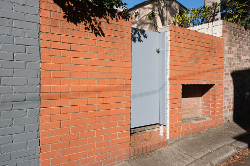 Orange brick wall with grey door on a sunny day.