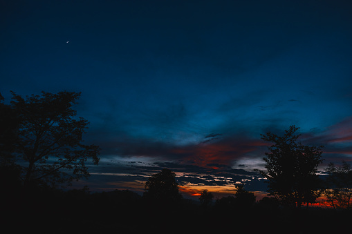 Dramatic orange clouds in the sky during sunset - Clouds in the sky background - Silhouette of tree in the foreground