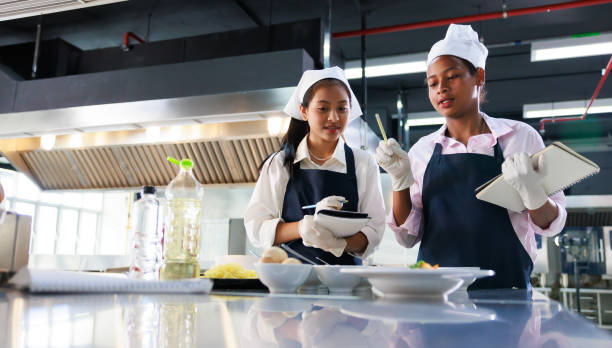 istock take note on book. Cooking class. culinary classroom. group of happy young woman multi-ethnic students are focusing on cooking lessons in a cooking school. 1564672198