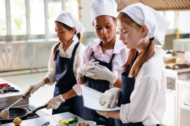 istock take note on book. Cooking class. culinary classroom. group of happy young woman multi-ethnic students are focusing on cooking lessons in a cooking school. 1564672234