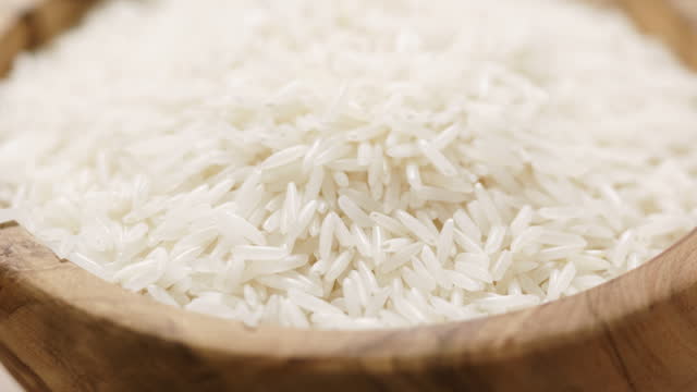 Closeup pan of dry basmati rice in wood bowl on table