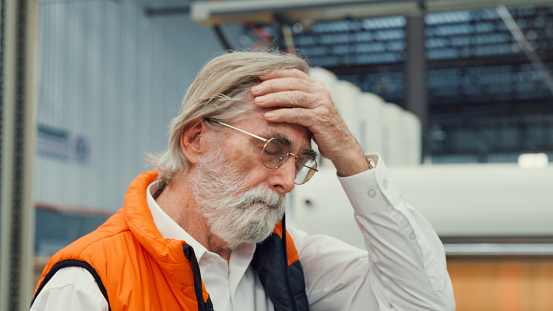 Professional male industrial engineers tired take off helmet in manufacturing factory. Working in manufacturing plant or production plant concept.