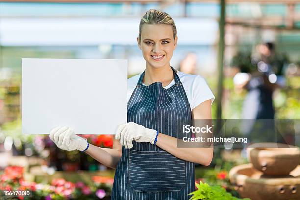 Foto de Jovem Mulher Segurando Placa Branca Florista Em Estufa e mais fotos de stock de Adulto