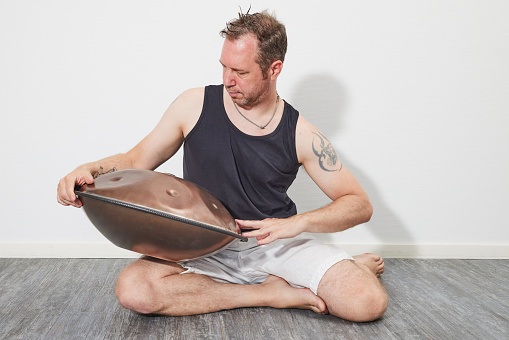 Man sitting on floor playing handpan