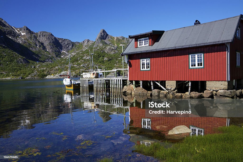 Fishing hut reflecting in fjord Typical red modern fishing hut on Lofoten islands in Norway reflecting in fjord Austvagoy Stock Photo