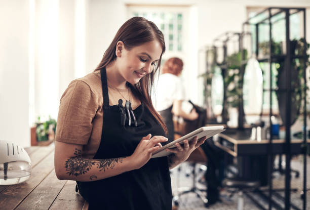 Shot of a hairstylist using a digital tablet at work