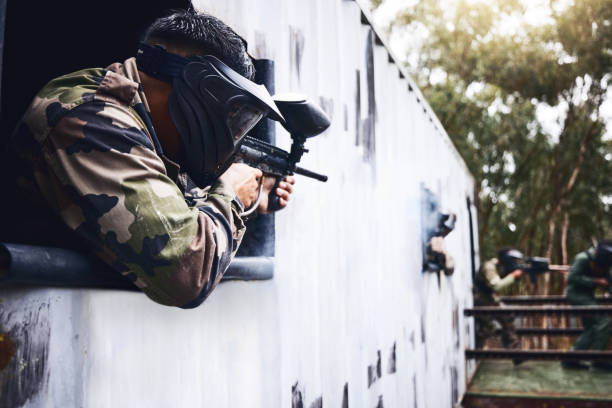 visez, tirez ou des personnes dans un jeu de tir de paintball avec une action rapide sur un champ de bataille amusant en vacances. homme en mission, jouant ou joueur avec un équipement d’armes militaires pour survivre dans une compétition en plein air - black and white military uniform headwear one person photos et images de collection