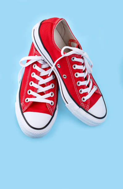 istock Red sneakers on blue background with copy space. Youth shoes. 1564732608