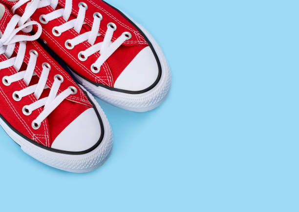 istock Red sneakers on blue background with copy space. Youth shoes. 1564734182
