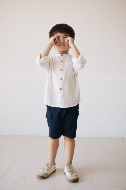 un retrato de un niño con una camisa blanca educada que muestra una expresión triste y llorando. - displeased child abandoned child abuse fotografías e imágenes de stock