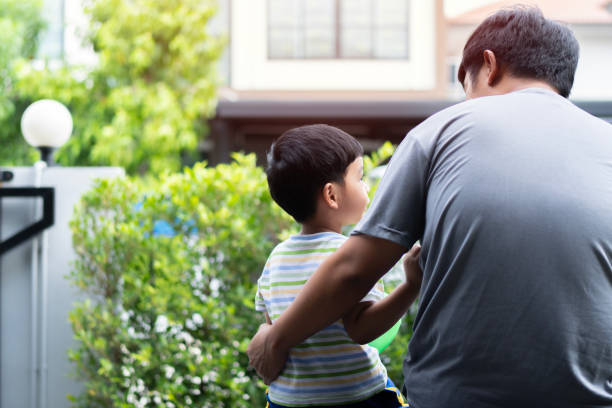 back view of handsome father and his cute son looking at each other and smiling while spending time together at home. - love growth time of day cheerful imagens e fotografias de stock