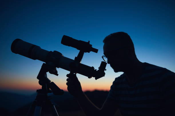 istock Astronomer looking at the starry skies and crescent Moon with a telescope. 1564794345