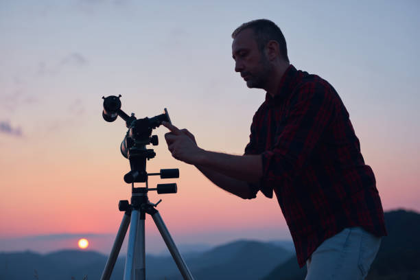 istock Astronomer looking at the sun with a telescope and using a cellphone. 1564795159