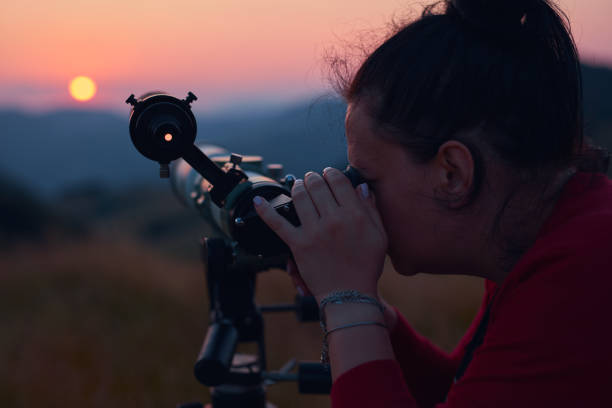 istock Female astronomer looking at the sun with a telescope. 1564799794