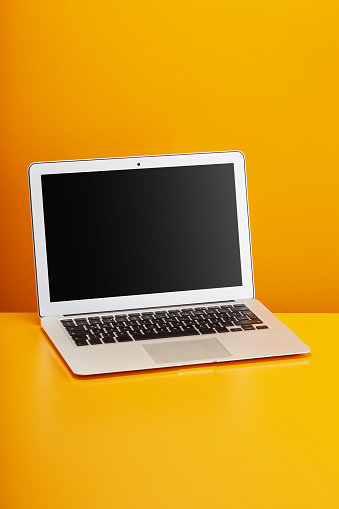 Real laptop computer on orange background with clipping path for the screen