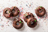 Dark brownie donuts made of sprinkles and chocolate.