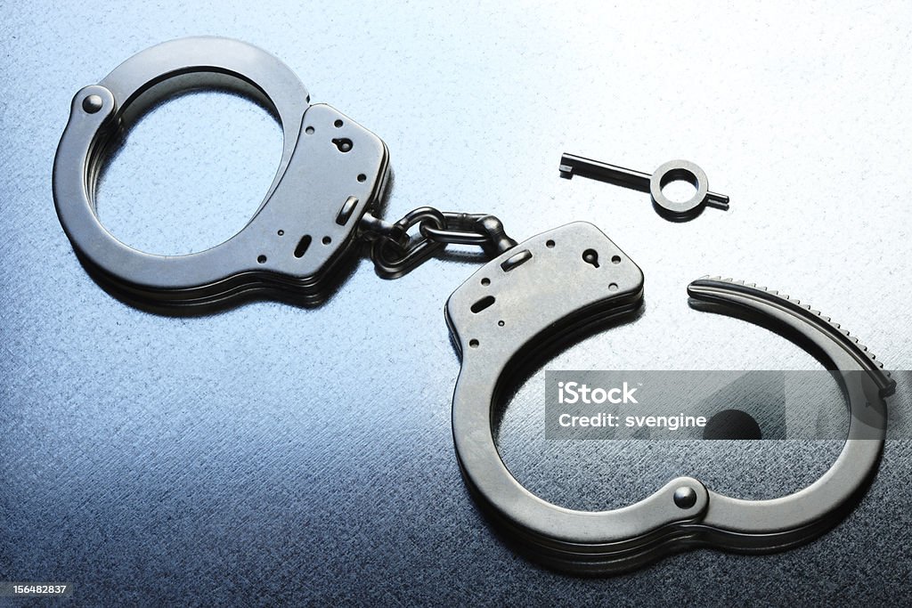 Handcuffs unlocked Pair of unlocked handcuffs with key shot on steely cool metallic background Chain - Object Stock Photo