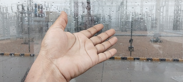 This is a picture of a human hand behind the glass window in Rainey weather at wind power plant