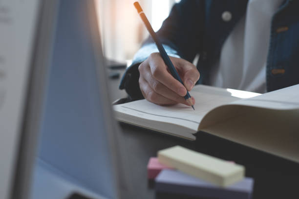 istock Event planner timetable agenda plan on year 2023 schedule event. Business woman checking timetable, taking note on calendar planner notebook on office table. Calendar event plan, work planning 1564849559