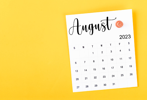 August 2023 and wooden push pin on yellow background.