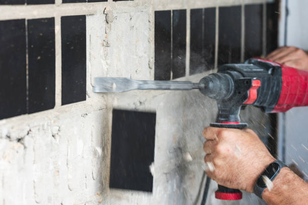 istock Builder with a puncher dismantles old tiles from a concrete wall 1564915989