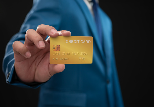 Businessman holding credit card on dark background. Shopping concept. Cashless spending concept. loan concept