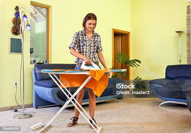 Hermosa Mujer Joven Tabla Su Ropa En Su Hogar Foto de stock y más banco de imágenes de Esposa - Cónyugue - Esposa - Cónyugue, Fémina, Mujeres