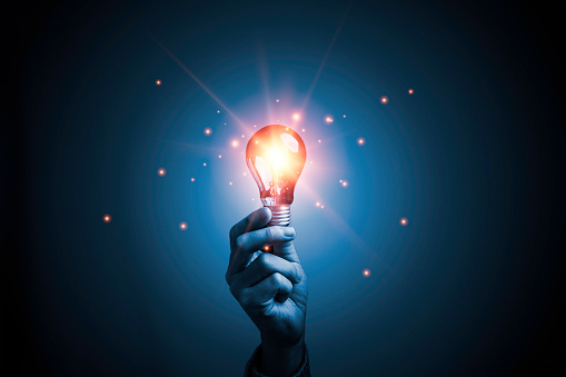Hand holding glowing lightbulb for creative thinking idea with solution problem solving and innovation concept.