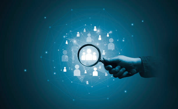 istock Hand holding magnifier glass with human icon for focus customer target of customer relation management or CRM and human development concept. 1564973429
