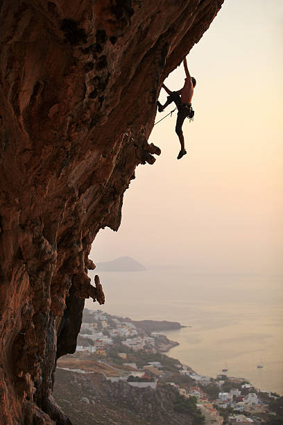 rock alpinista ao pôr do sol - climbing men sea cliff imagens e fotografias de stock