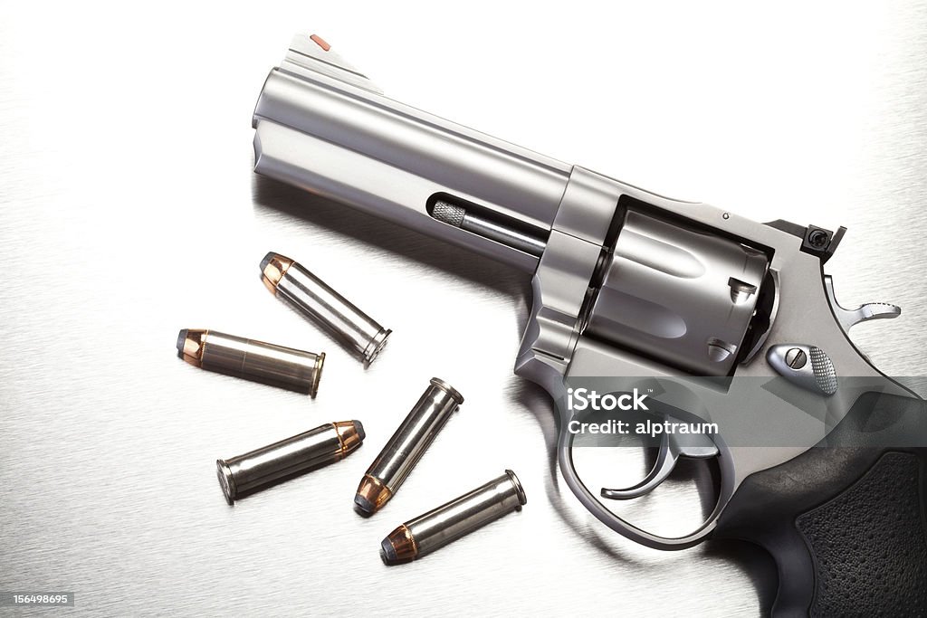 gun with bullets on steel gun with bullets on steel surface - modern revolver handgun Ammunition Stock Photo