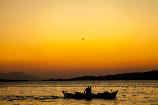 Silhouette of small fishing boat in the sea at sunset in Ayvalık