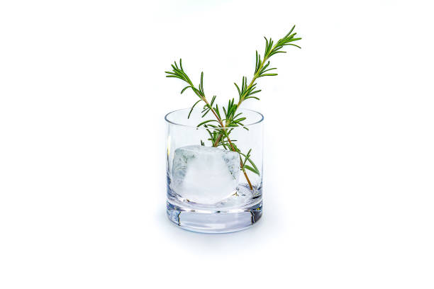 Glass with ice cube isolated in the studio Tumbler glass with a large ice cube and rosemary isolated in the studio water thinking bubble drop stock pictures, royalty-free photos & images
