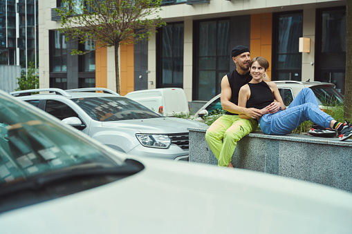 Couple in love is resting on a city walk, the guy hugs his girlfriend, nearby car parking