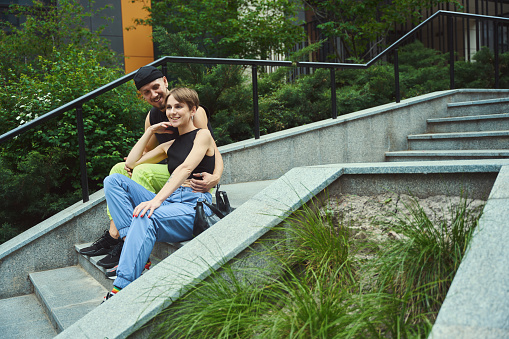 Caucasian man and woman showing affection to each other while sitting on stairs outside